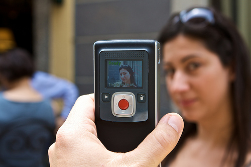 A man shoots a video of a young woman